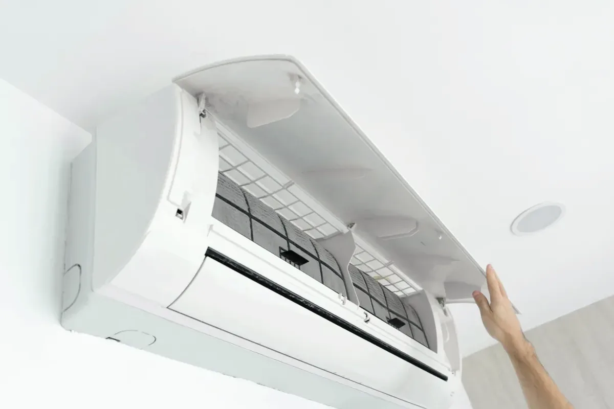 Hand opening the cover of a wall-mounted ductless air conditioner